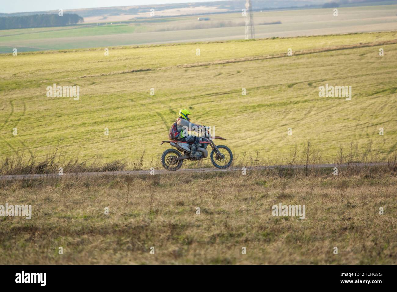 a motor cyclist (biker) riding his offroad motorbike along a stone