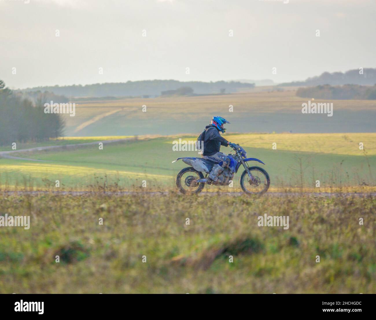 a motor cyclist (biker) riding his offroad motorbike along a stone
