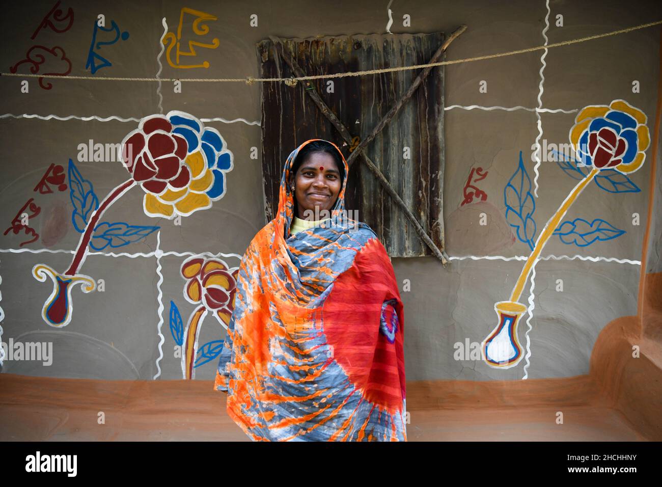 Rajshahi, Bangladesh. 25th Dec, 2021. Santali woman poses for a photo in front of her painted house in Rajshahi. Santal tribe is an ethnic group native to eastern India. Santals are the largest tribe in the Jharkhand state of India in terms of population and are also found in the states of Assam, Tripura, Bihar, Odisha and West Bengal. They are the largest ethnic minority in northern Bangladesh's Rajshahi Division and Rangpur Division. (Photo by Piyas Biswas/SOPA Images/Sipa USA) Credit: Sipa USA/Alamy Live News Stock Photo