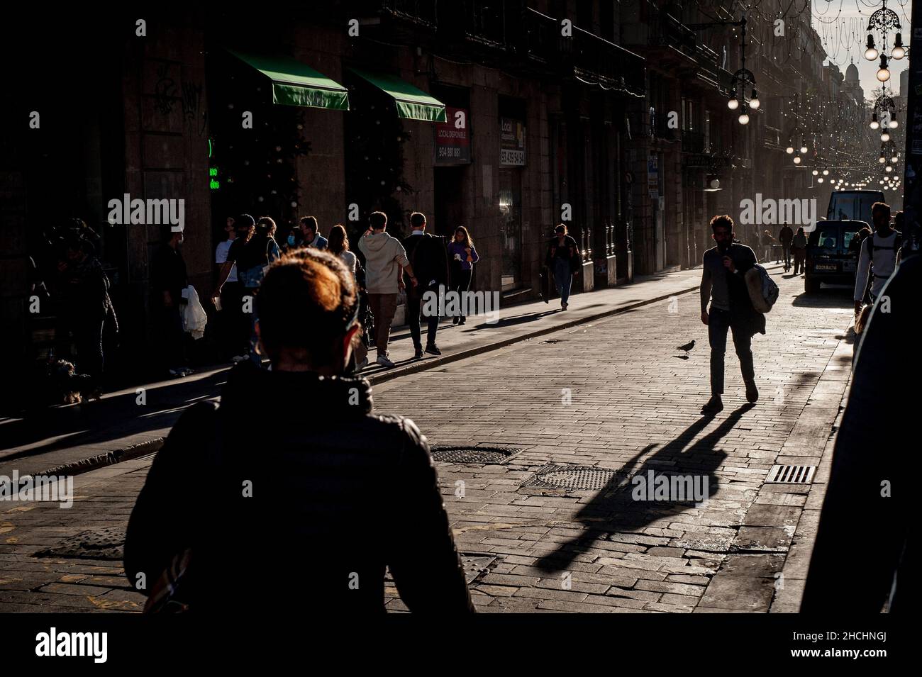 Commuters walk along Ferran street in downtown Barcelona. The sixth wave of the coronavirus in Spain continues to break new records in terms of daily infections, Spanish Health Ministry reported 99,671 cases on Tuesday. Majority of new infections already correspond to the Omicron variant. Stock Photo