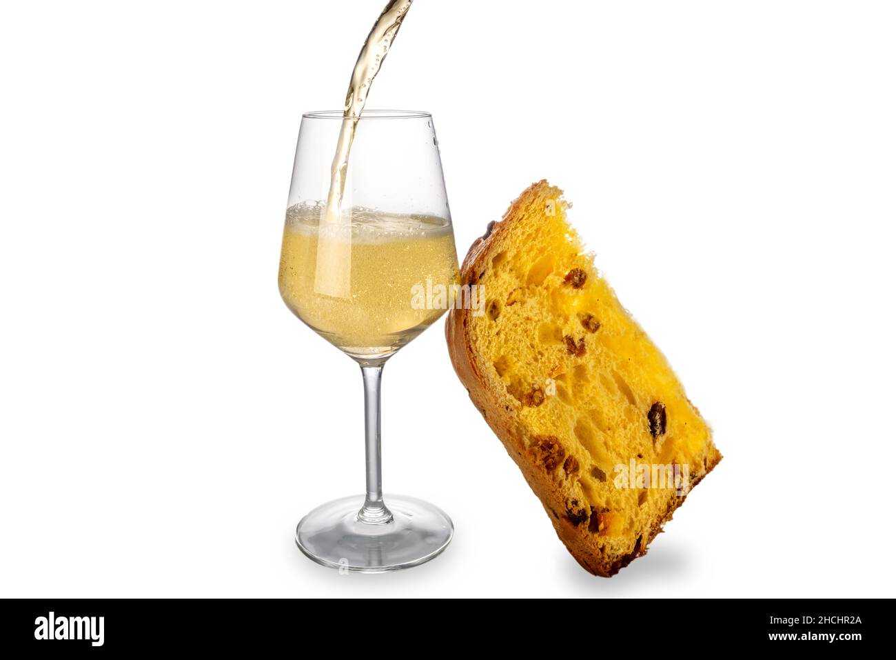 Champagne or sparkling wine splashing into glass with slice of panettone cake, isolated on white. Christmas, New Year celebrations concept. Copy space Stock Photo