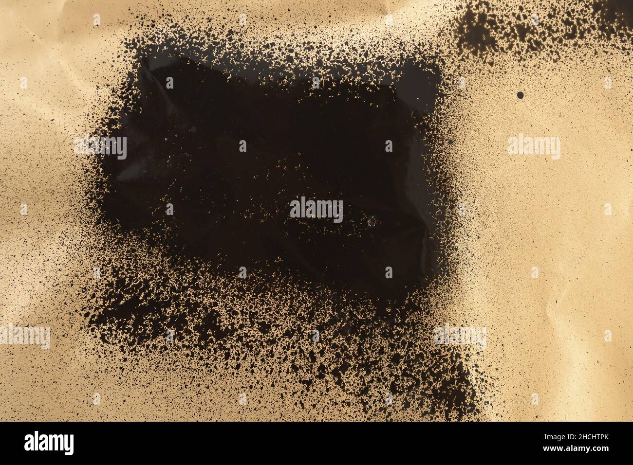 black stain of spray paint on a gold colored paper Stock Photo - Alamy