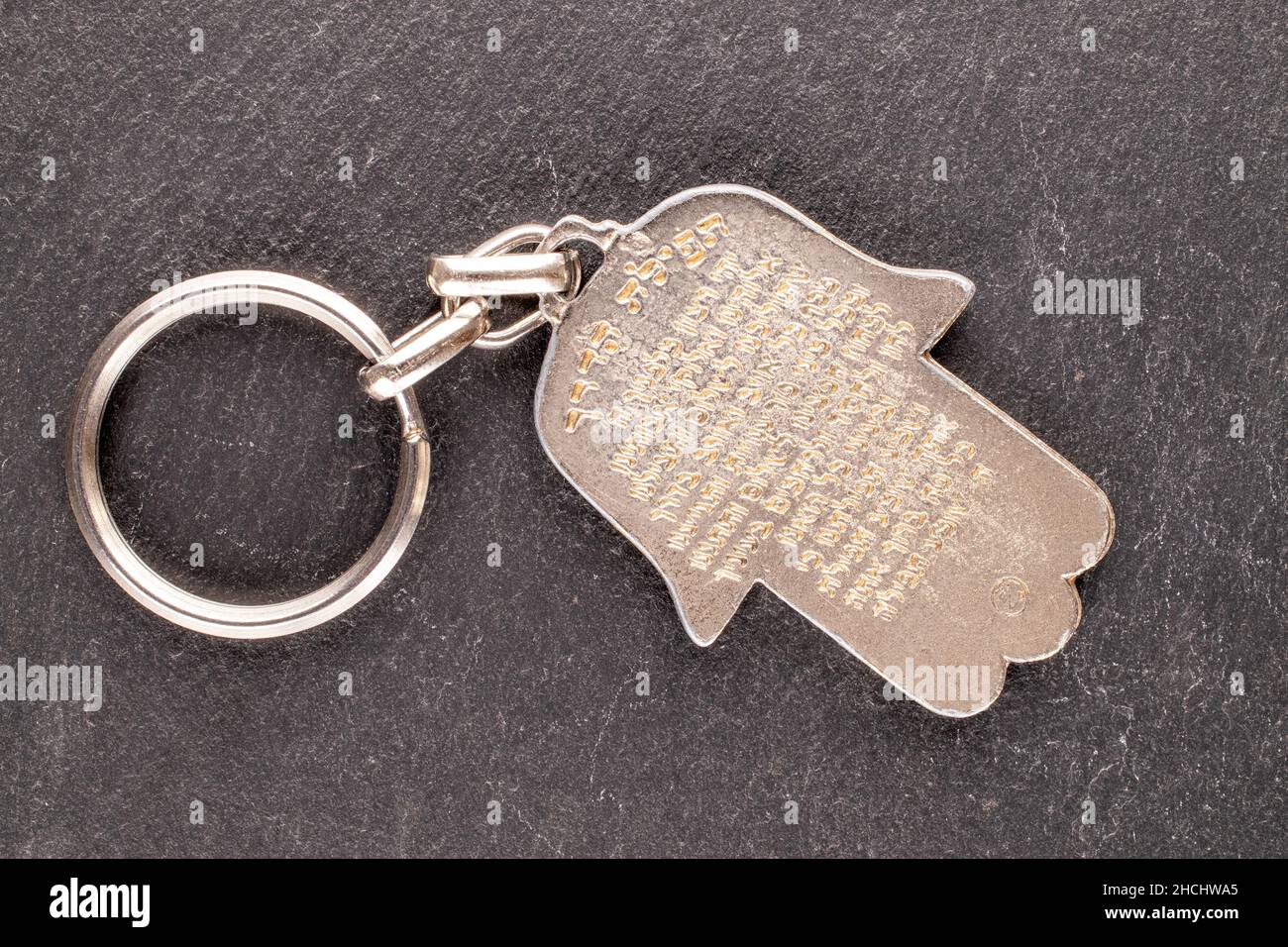 One metal keychain, the Jewish 'hand of Miriam' on a slate stone, close-up, top view. Stock Photo