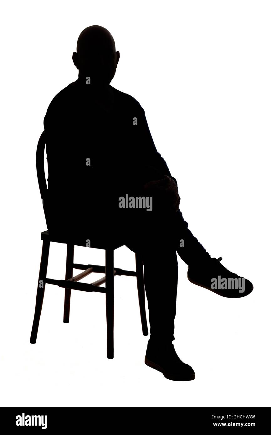 front view of the silhouette of a man sitting on chair with casual clothes with his legs crossed