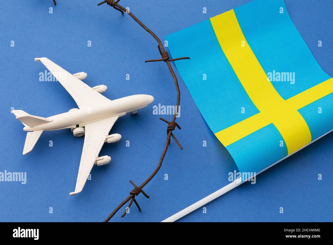 Toy plane, Swedish flag and barbed wire on blue background, Sweden air border violation concept Stock Photo