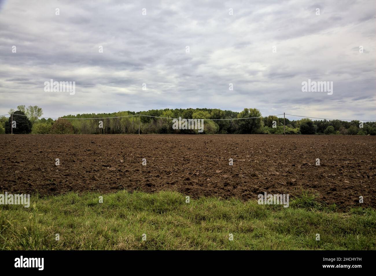 Electricity pylons and power lines in a ploughed field on a cloudy day ...
