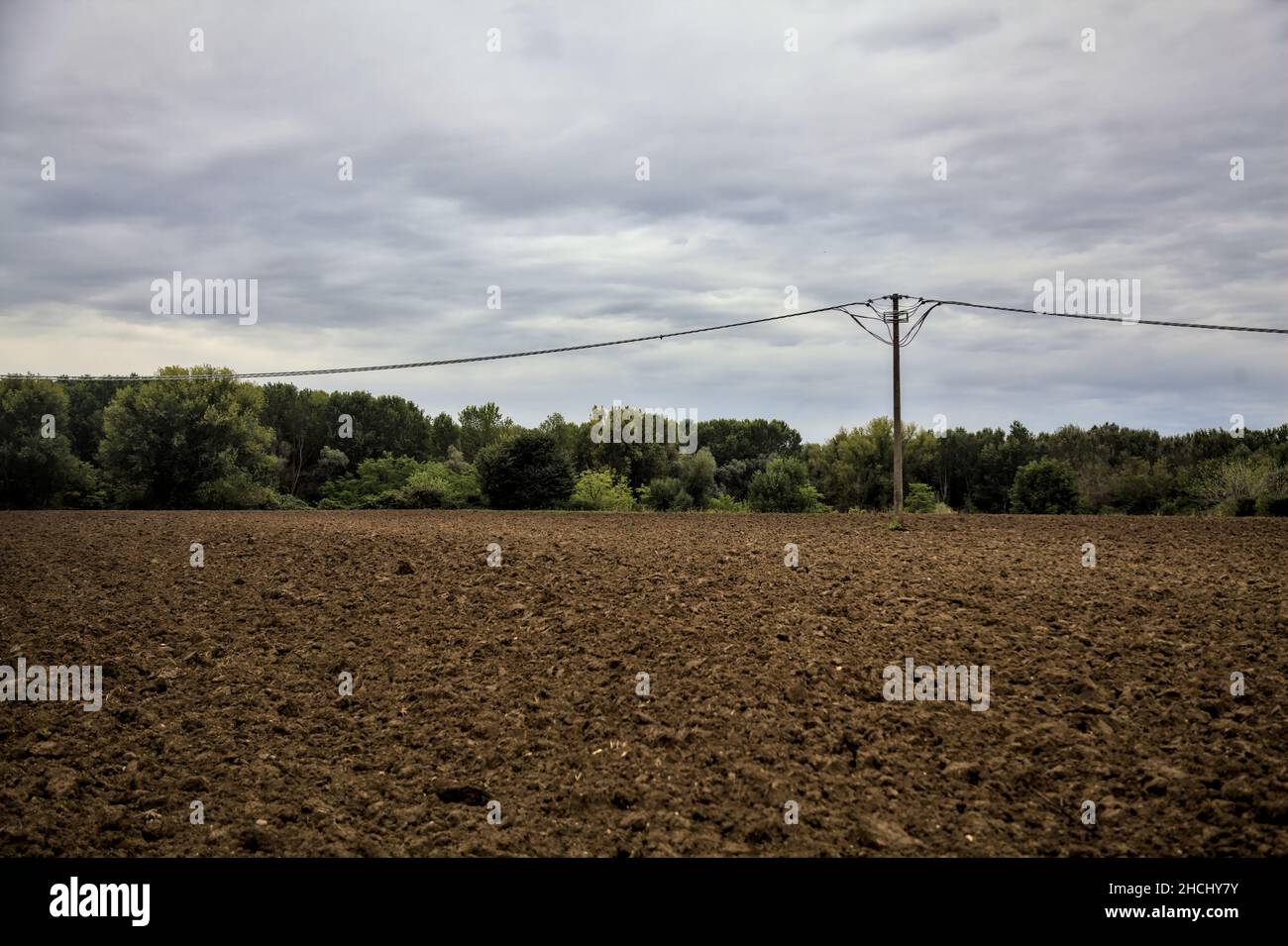 Electricity pylons and power lines in a ploughed field on a cloudy day ...