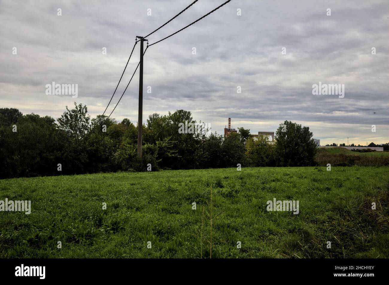 Field with electricity pylons and trees in the italian countryside on a ...
