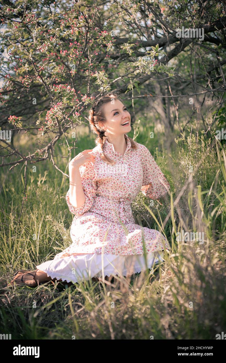 Beautiful woman in the garden among blooming apple trees in a vintage dress. Stock Photo