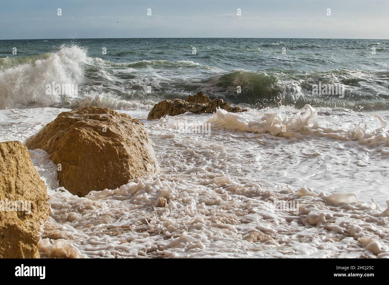 Large waves break on boulders on the coast of the Algarve, Portugal Stock Photo