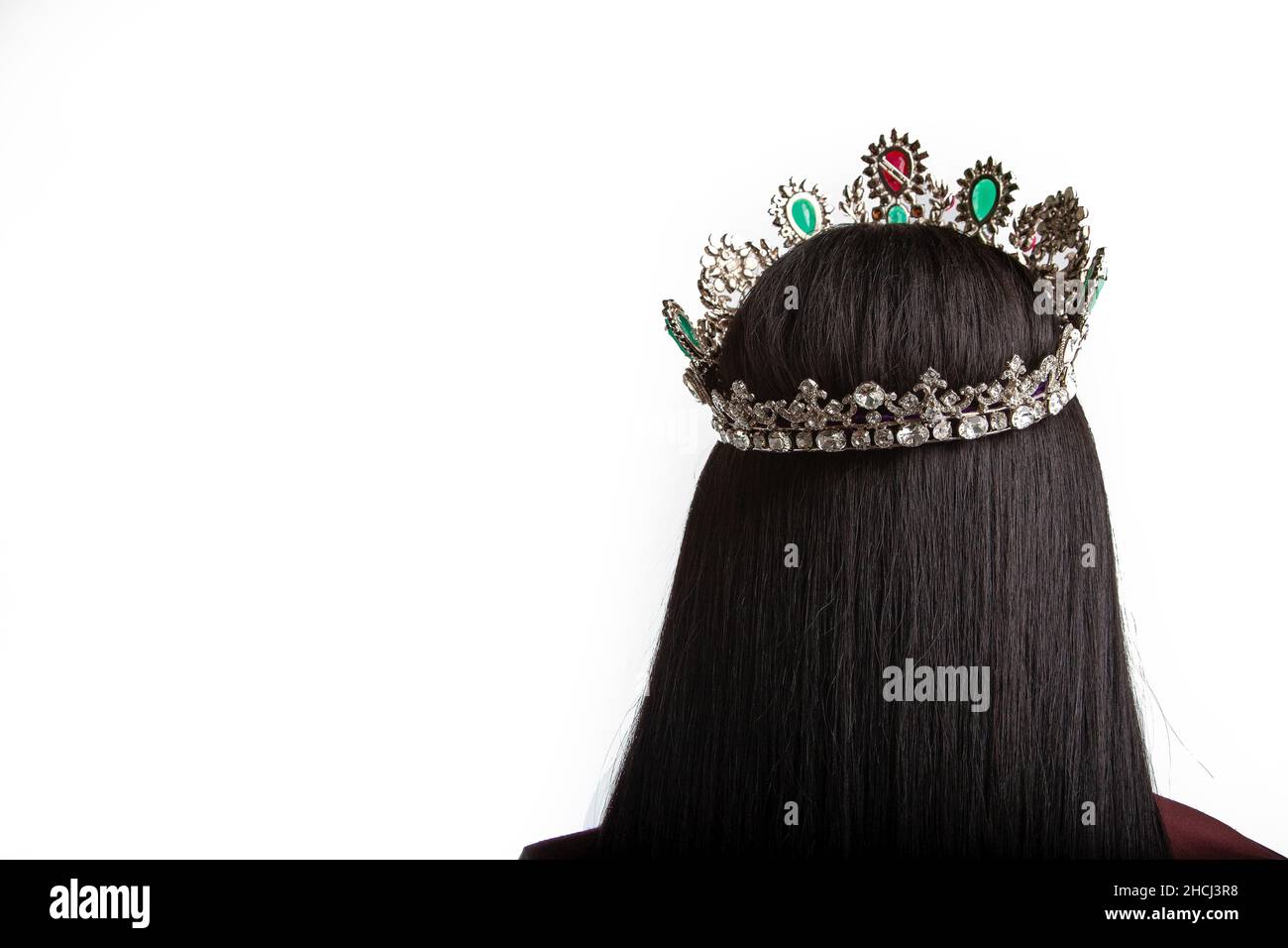 Beautiful shot of a black haired girl standing backwards with a crown on a head Stock Photo
