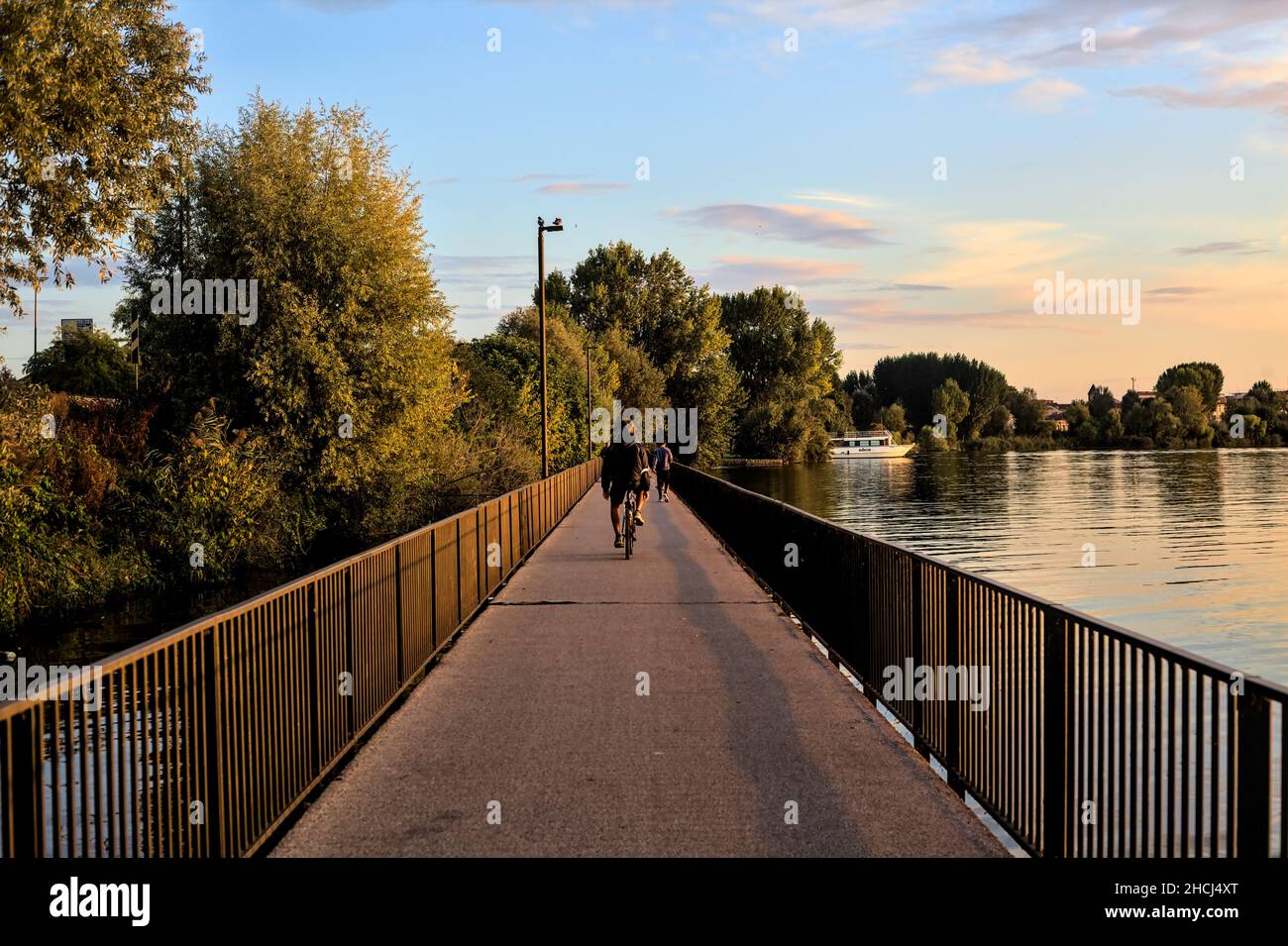 Passageway over a lake at sunset with people strolling by Stock Photo
