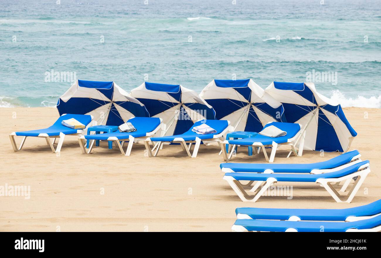 towels on sunbeds, sunloungers on beach in Spain Stock Photo