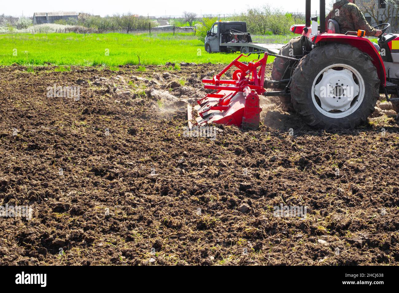 A tractor plows the land in a garden plot on a spring day. Agriculture and Agronomy. Stock Photo