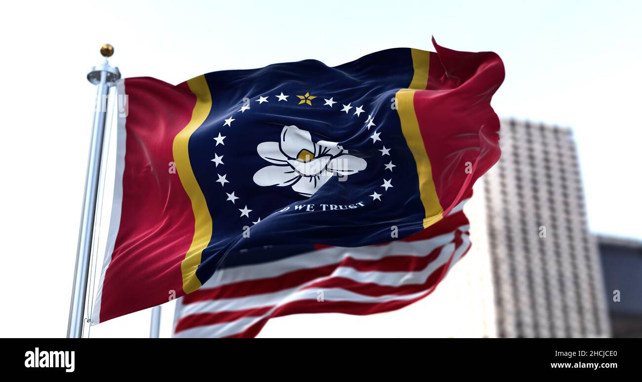 the flag of the US state of Mississippi waving in the wind with the American flag blurred in the background. Mississippi was admitted to the Union on Stock Photo