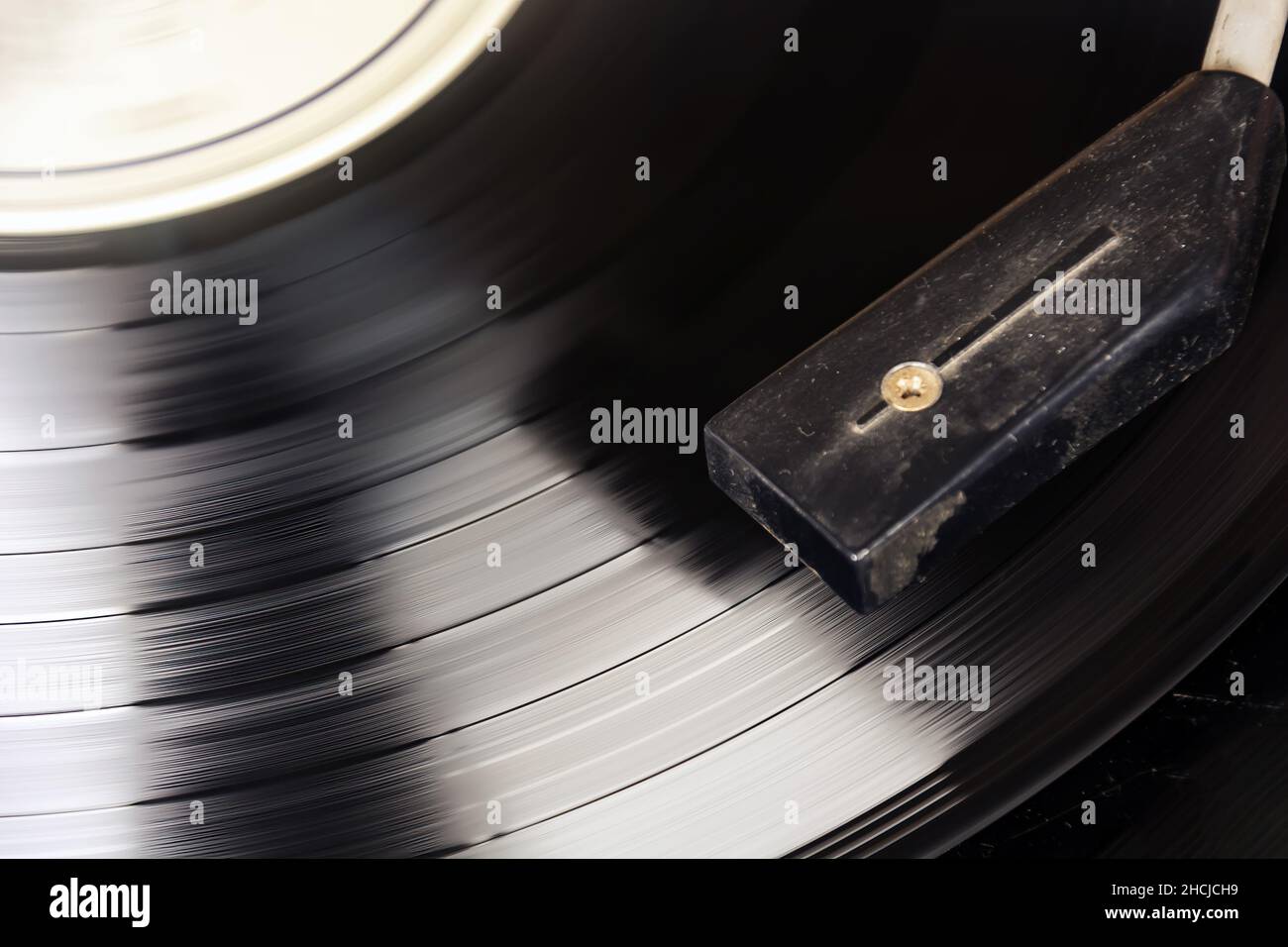Black vinyl record spinning on the turntable. Analog audio playback. Furrows of music tracks. Long playing and vintage object Stock Photo