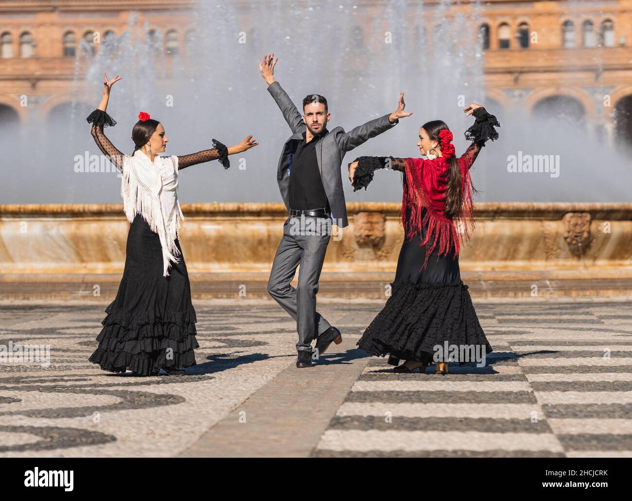 Three people with flamenco outfit dancing in a traditional square Stock Photo