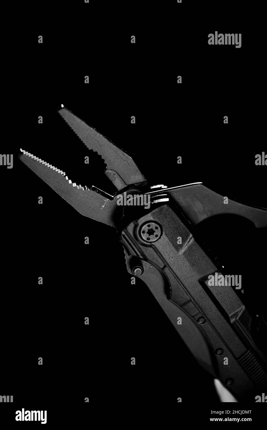 Vertical grayscale shot of pliers tool against a dark background Stock Photo