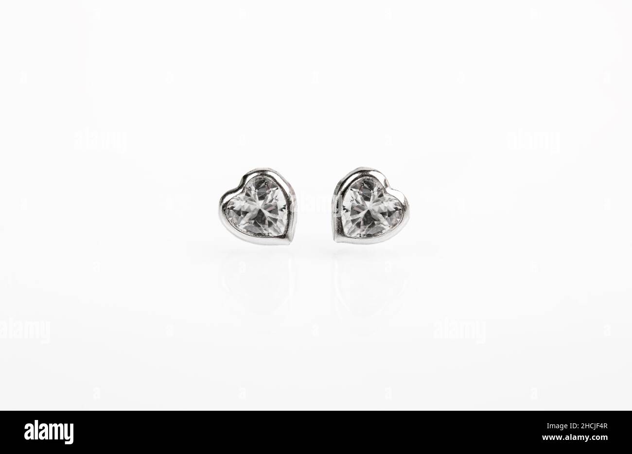 Hearts-shaped silver stud earrings on white background. Stock Photo