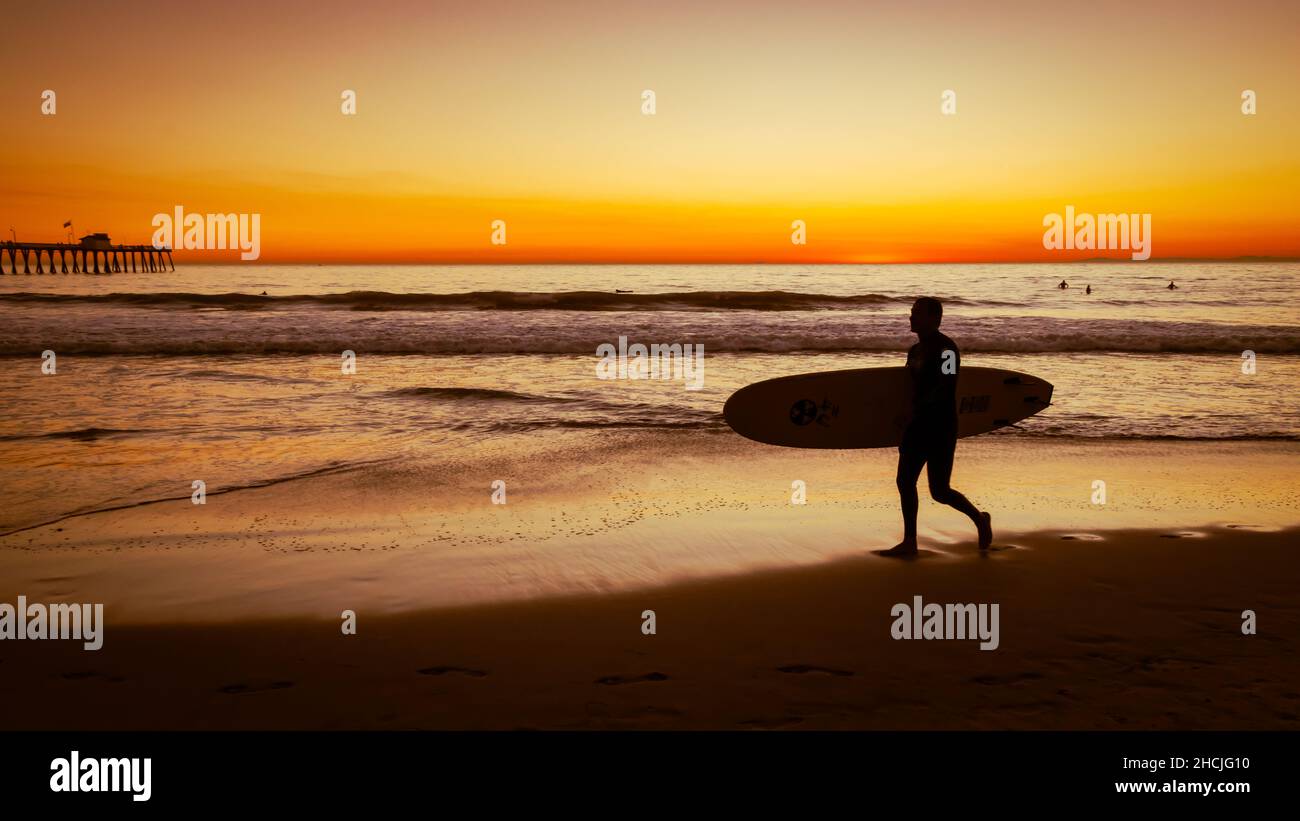 Silhouette of a guy walking with surfboard at the San Clemente beach during sunset Stock Photo