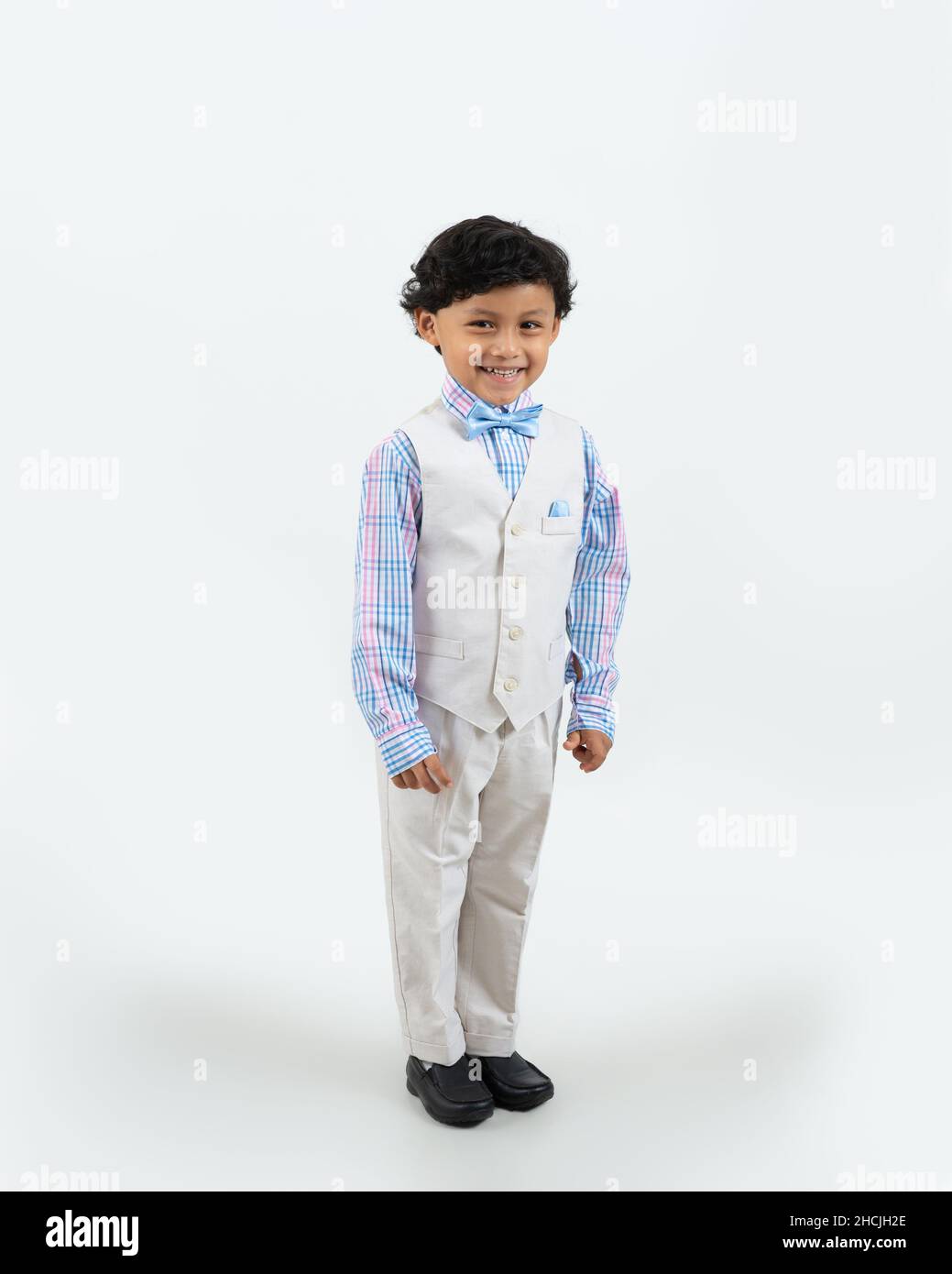 Closeup portrait of 4 or 5 year old boy, smiling, white background,  full length, wearing formal white suit Stock Photo