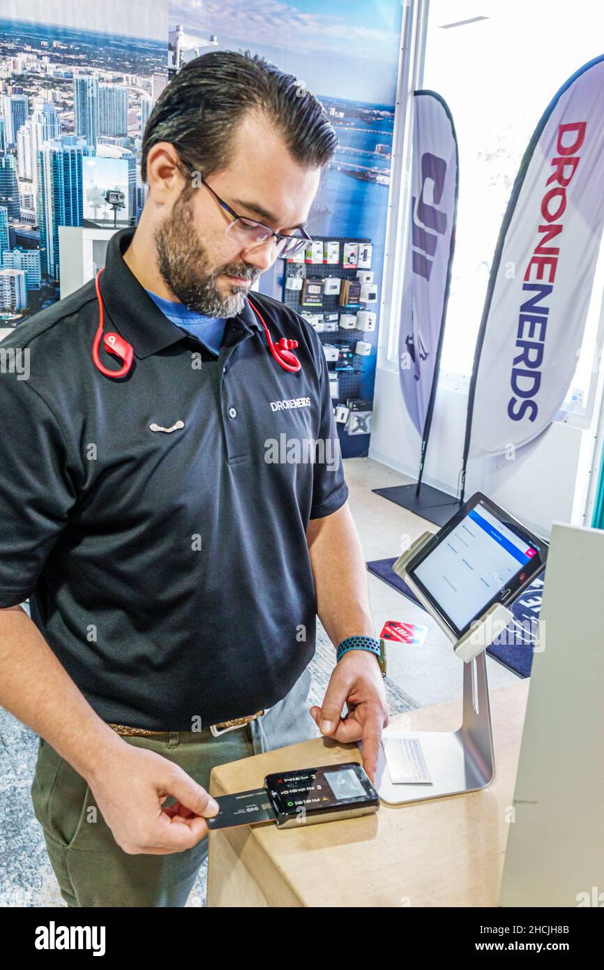 Miami Florida Aventura Drone Nerds inside interior store employee man male salesman scanning credit card scanner Stock Photo