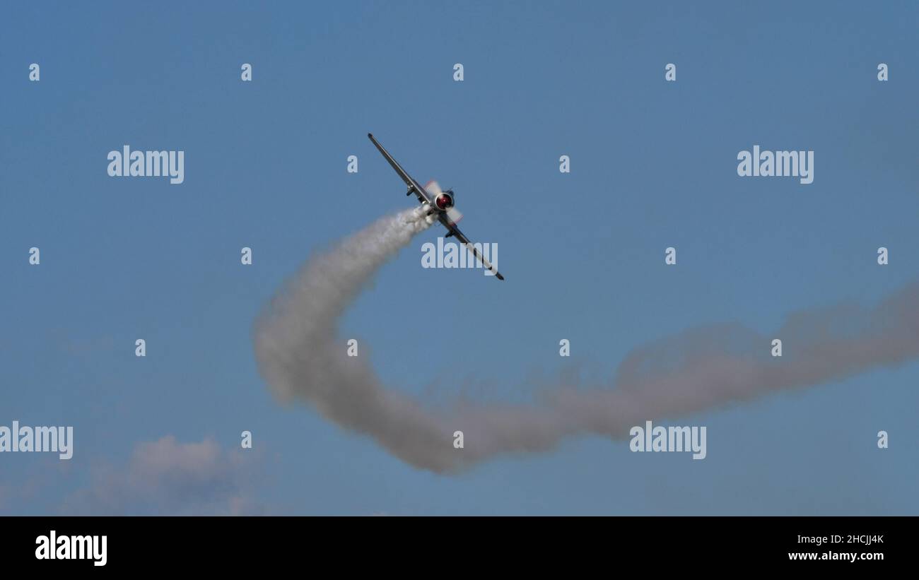 Thiene Italy OCTOBER, 16, 2021 Airplane in the blue sky made a left turn with white smoke. Copy space. Yakovlev Yak-52 by YAK Italia Stock Photo