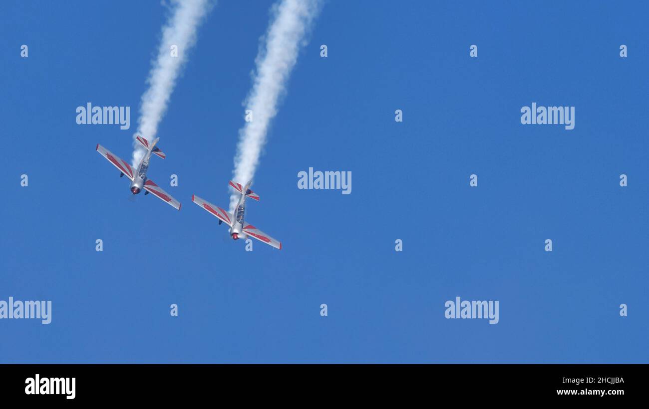 Thiene Italy OCTOBER, 16, 2021 Two propeller planes do a looping with white smoke in the blue sky with copy space. Yakovlev Yak-52 by YAK Italia Stock Photo