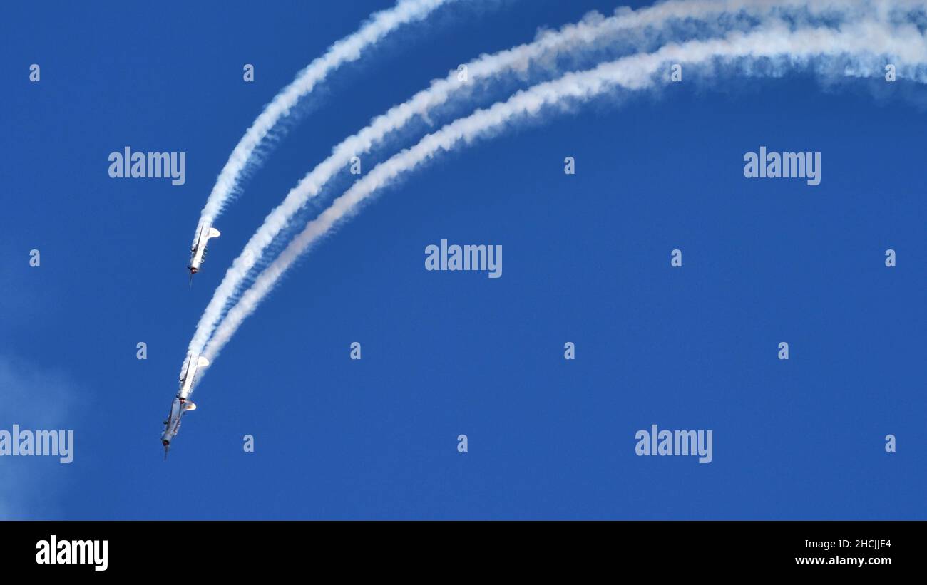Thiene Italy OCTOBER, 16, 2021 Aircrafts paint a loop in the blue sky with white smokes during an airshow. Yakovlev Yak-52 by YAK Italia Stock Photo