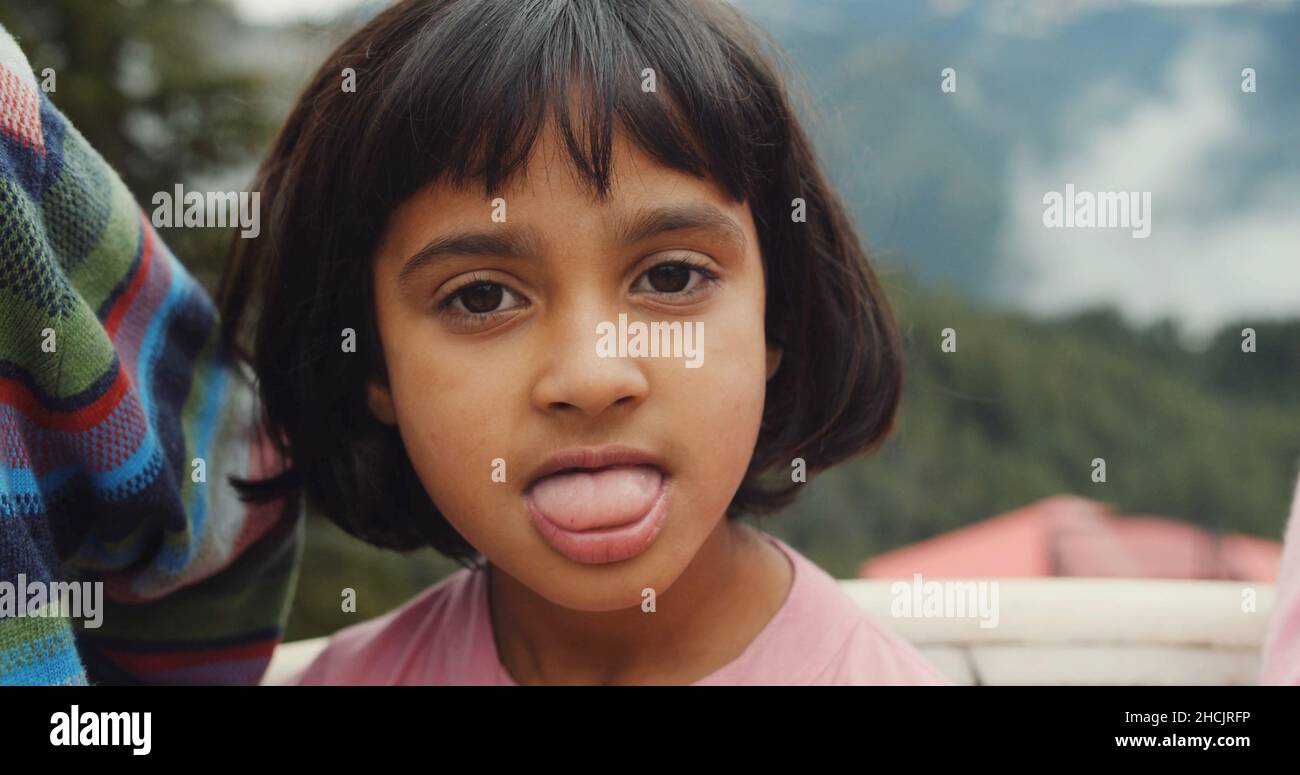 Portrait of a cute Indian girl with a short haircut and bangs showing her  tongue to the viewer Stock Photo - Alamy