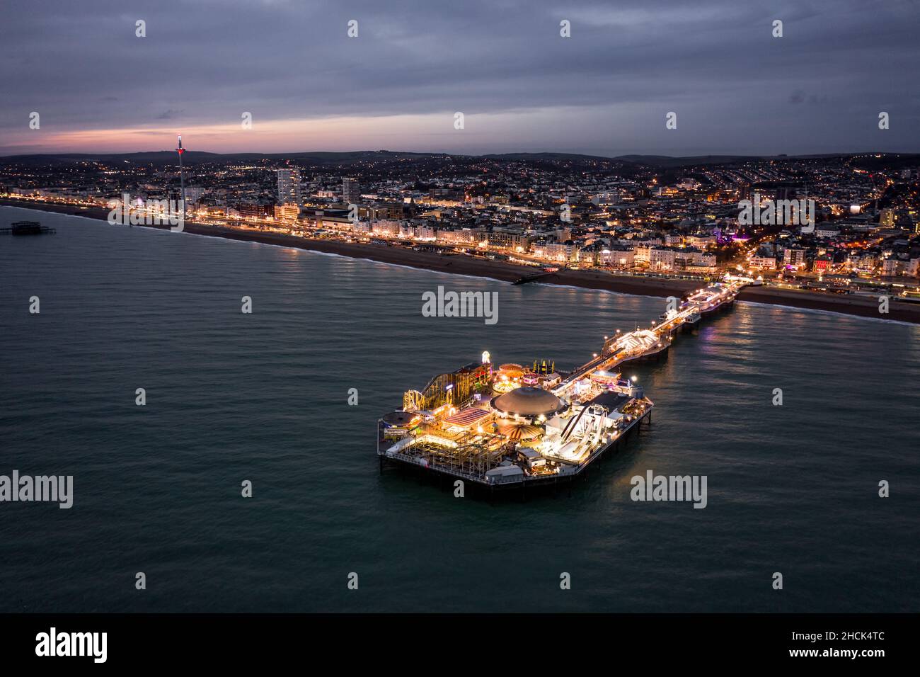 the-seafront-palace-pier-in-brighton-illuminated-at-night-aerial-view