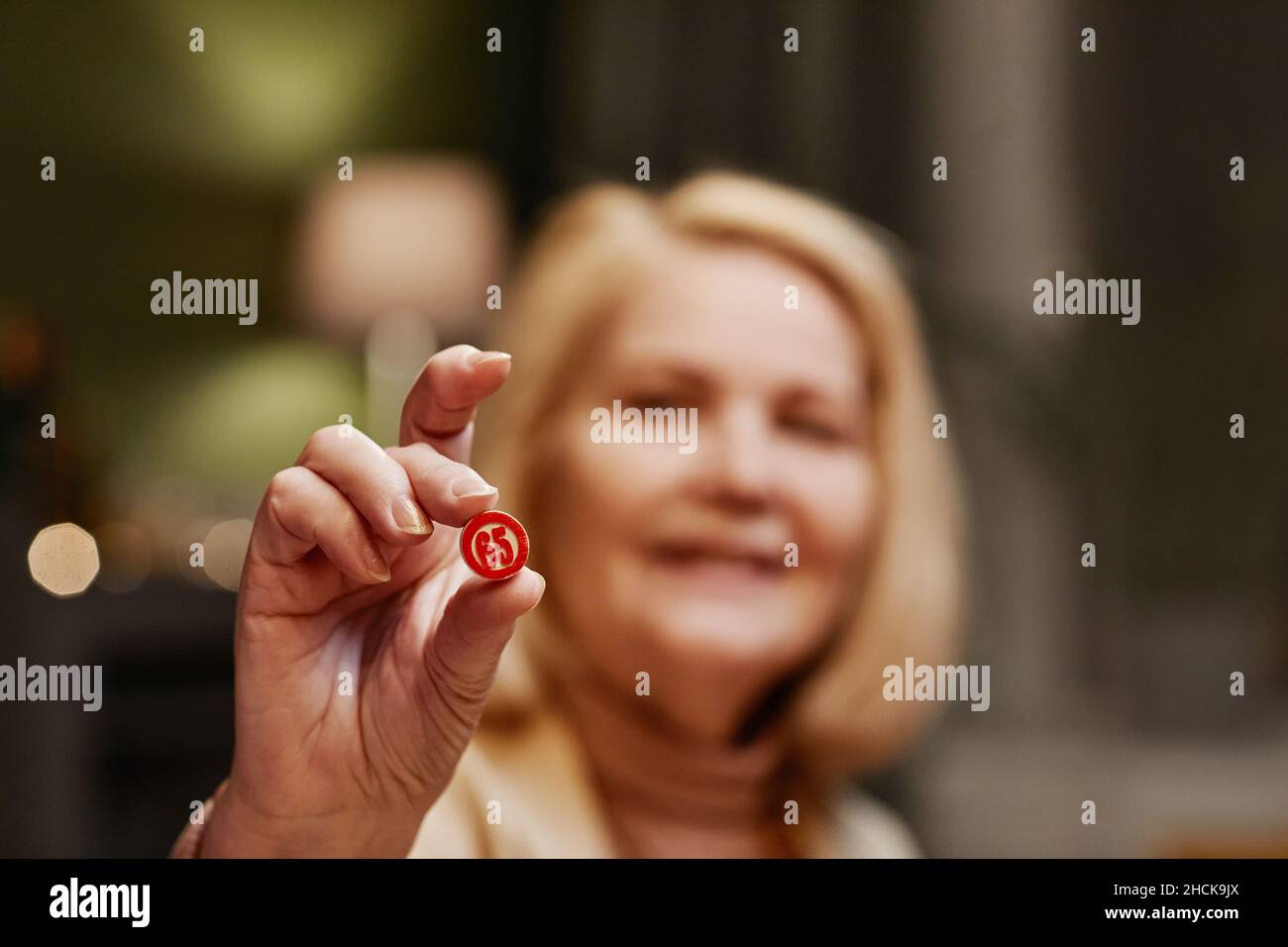 Hand of aged Caucasian woman holding dice with sixty five number while