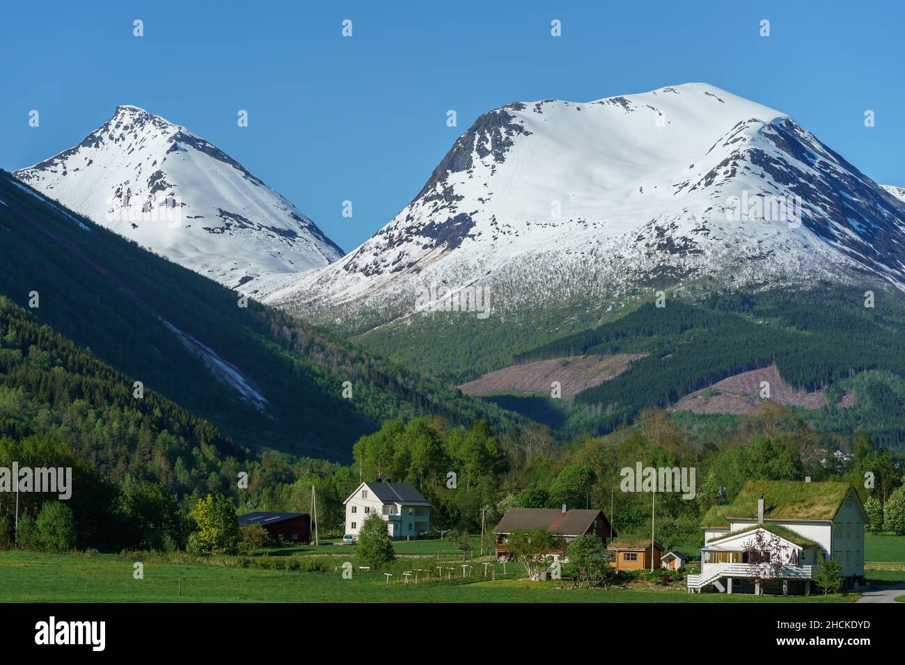 VALLDAL, NORWAY - 2020 MAY 30. Valldal valley with houses and mountains with snow on. Stock Photo
