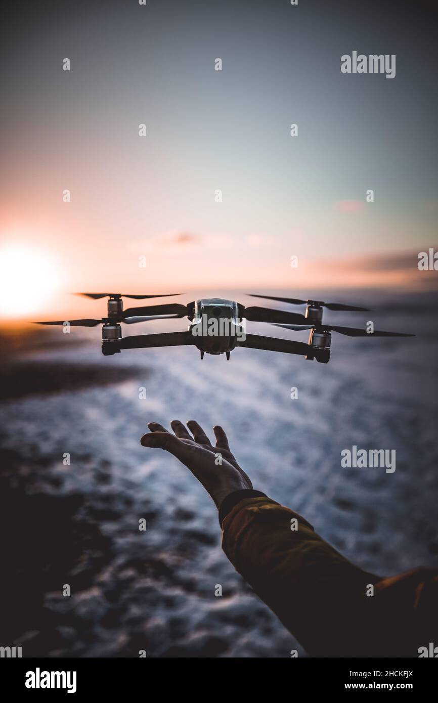 A Drone Landing in the Palm of a Hand at Sunset Stock Photo