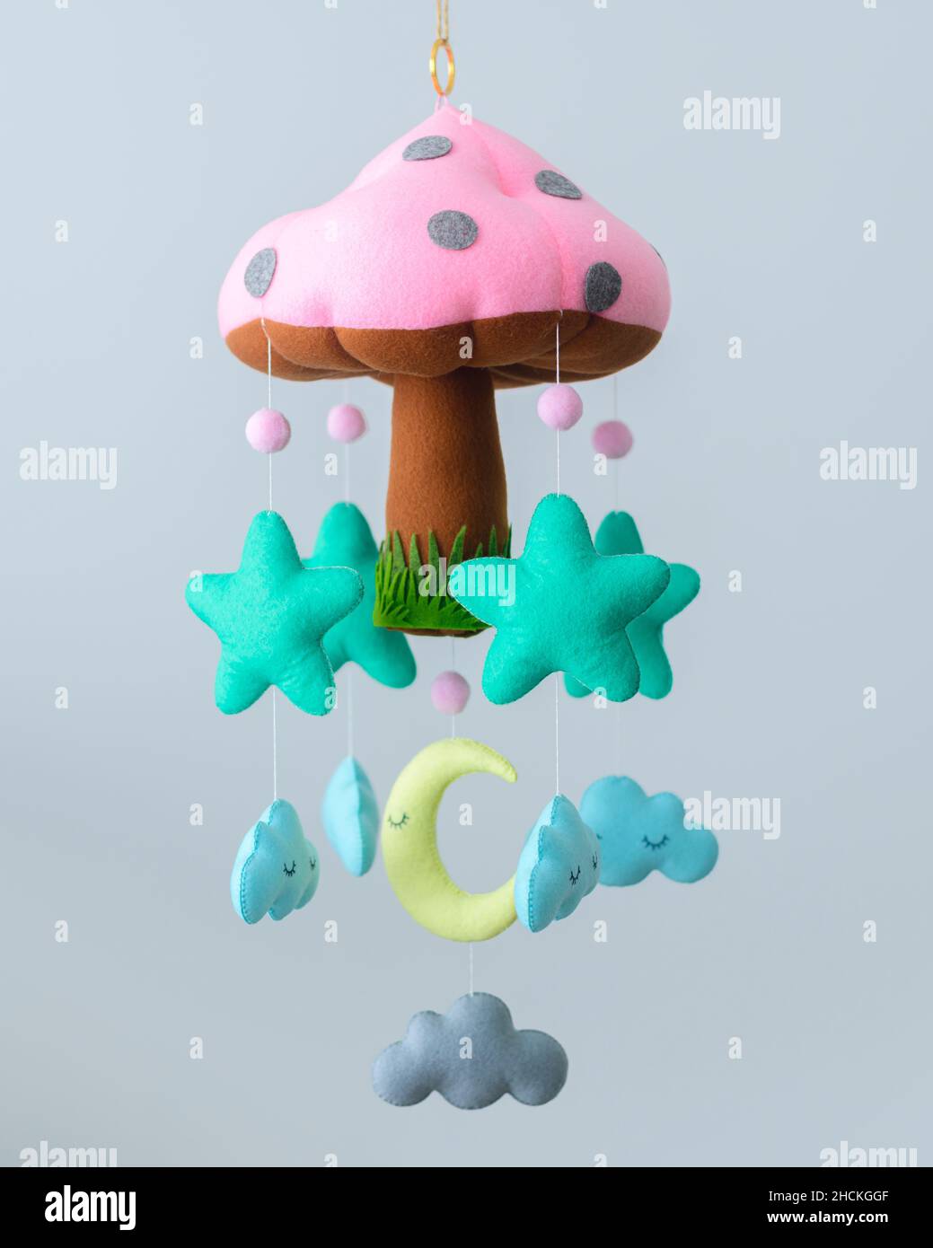 Beautiful Baby Cot mobile, Plushie mushroom with stars, clouds, and the moon hanging from strings. Nursery decor to calm and dream sleep for babies. Stock Photo