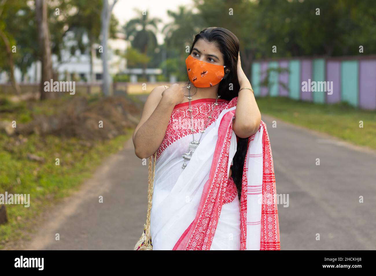 A pretty Indian woman in red saree and long hair wearing protective cotton  nose mask walking on road Stock Photo - Alamy