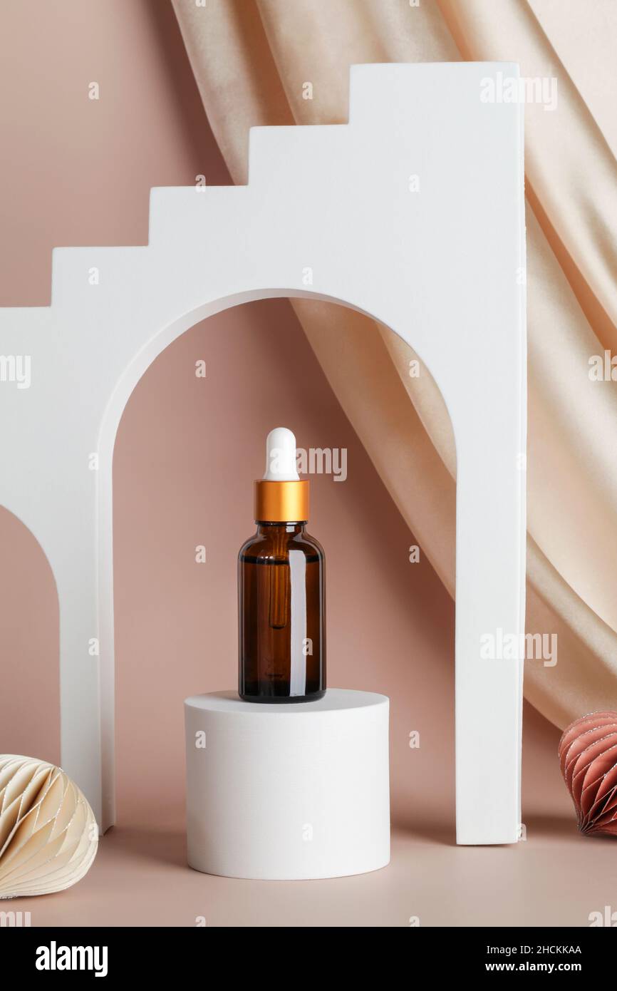 Serum essence on podium stage and geometric arches on beige background with textile and honeycomb paper decor. Skincare cosmetic in holiday concept Stock Photo