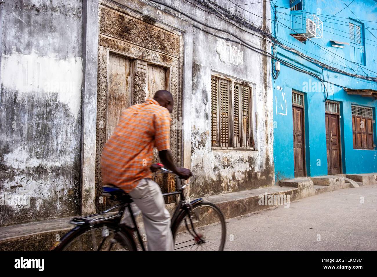 A local on his bicycle in a nattow alleway in Stone Town, Zanzibar, Tanzania. Stock Photo