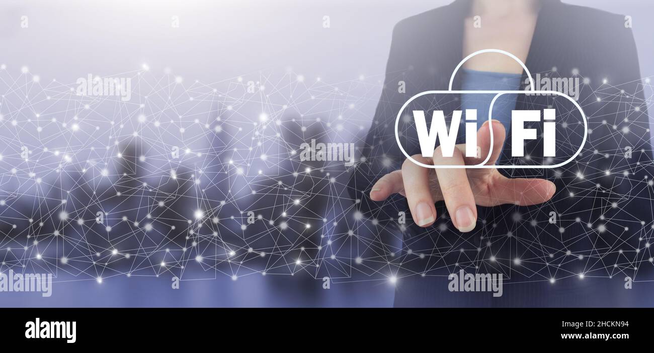 Free WiFi network signal technology internet concept. Hand touch digital screen hologram Wi Fi sign on city light blurred background. Wi Fi wireless c Stock Photo