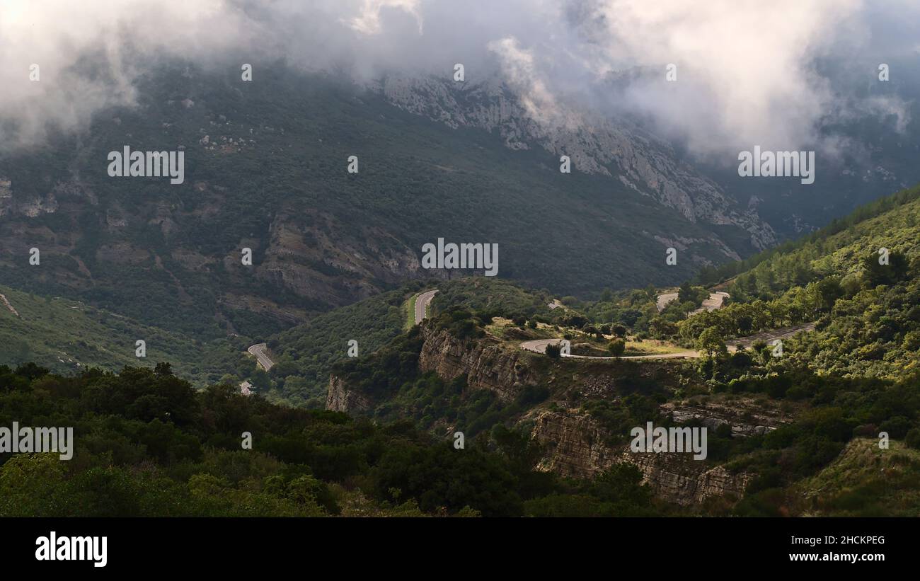 Beautiful view of mountain range Massif de la Sainte-Baume in Provence, France on cloudy day in autumn with winding country road D2 and rocks. Stock Photo