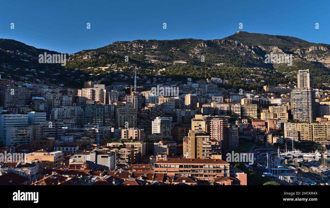 Beautiful panoramic view of the downtown of Monaco at the mediterranean coast in the afternoon sunlight with dense development surrounded by hills. Stock Photo