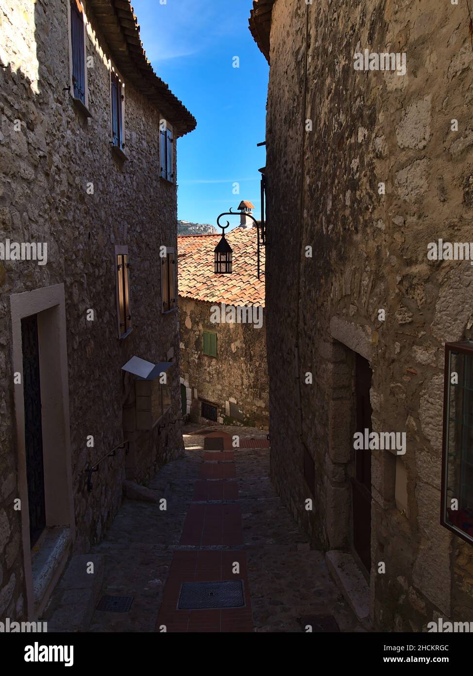 Beautiful view of a narrow, empty alley between traditional stone houses in the historic center of small village Eze at the French Riviera. Stock Photo