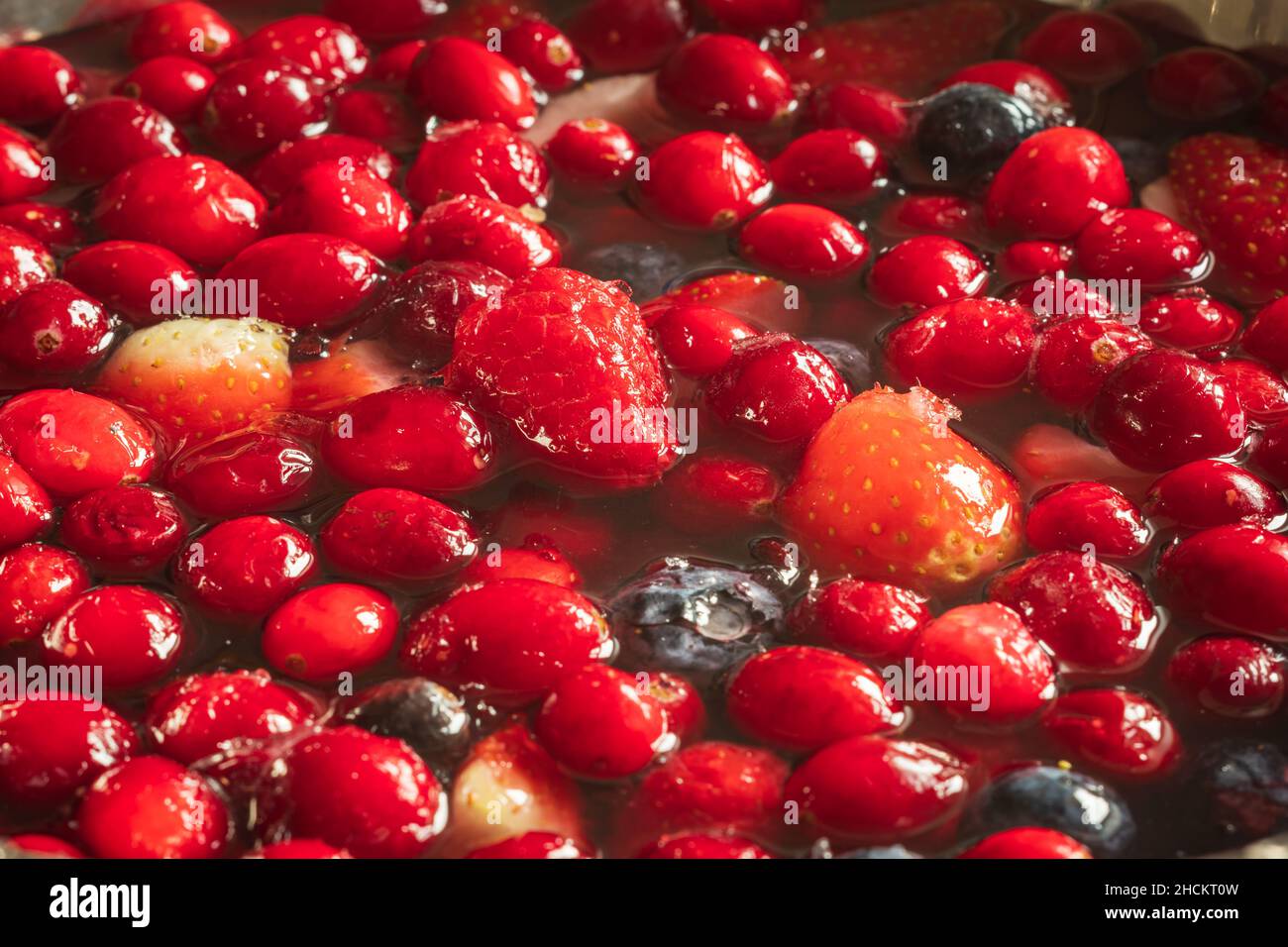 frozen mix strawberries blueberries raspberries and cranberries in water closeup Stock Photo