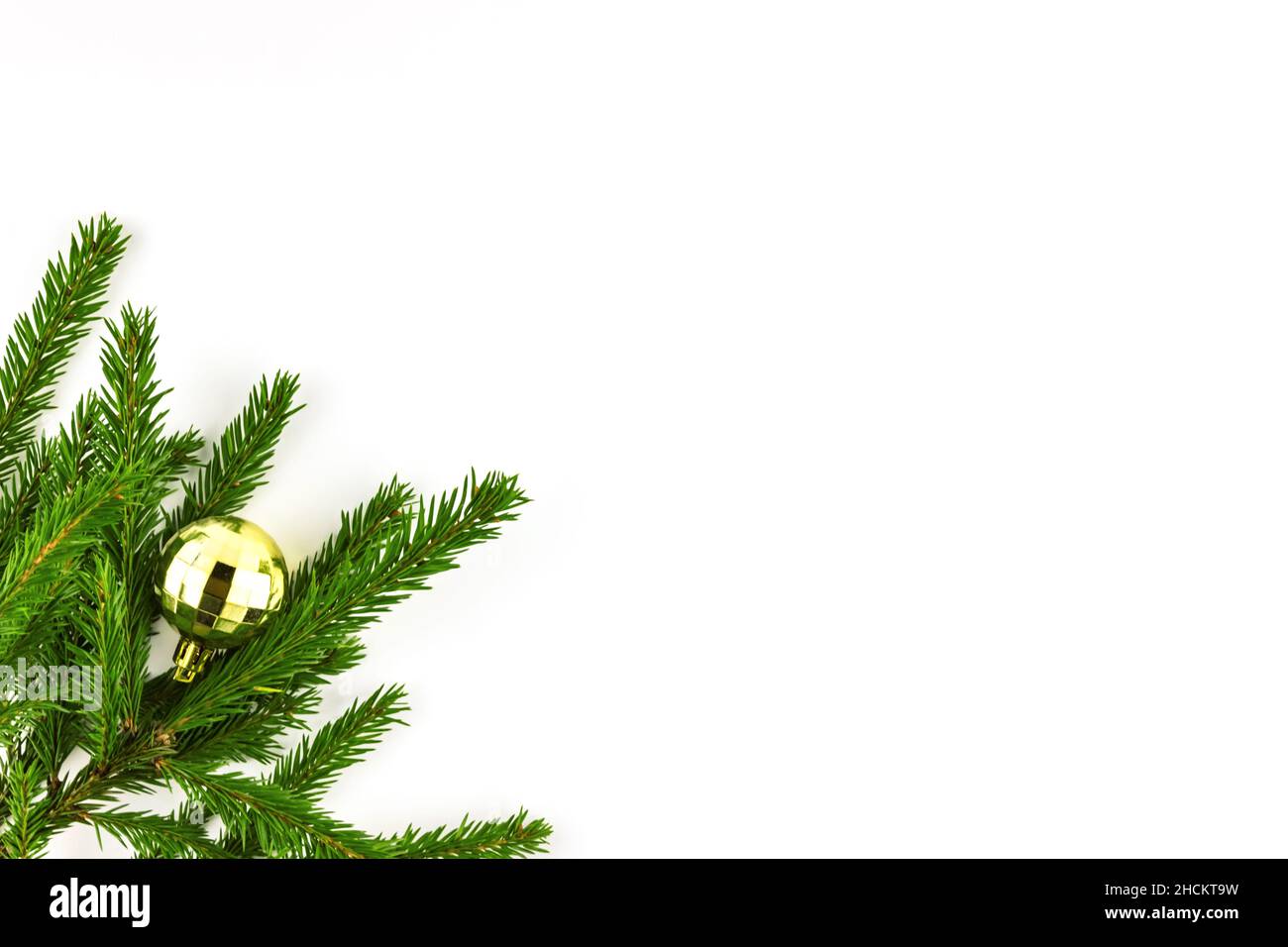 Christmas ball toy faceted decoration golden color on fir tree branch isolated on white background Stock Photo