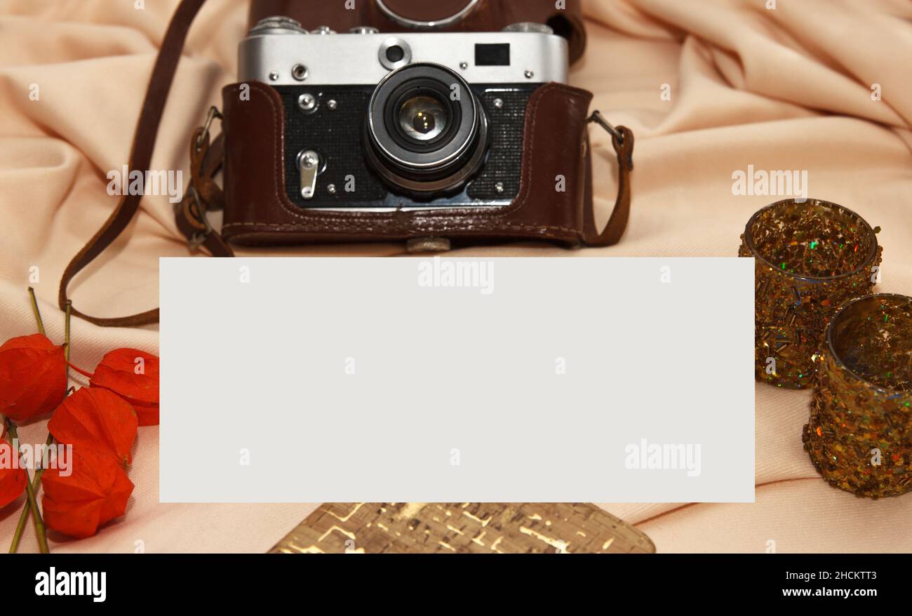 Flatlay. Film camera in case, notebook, fisalis and candlesticks lie on a light beige background. Stock Photo