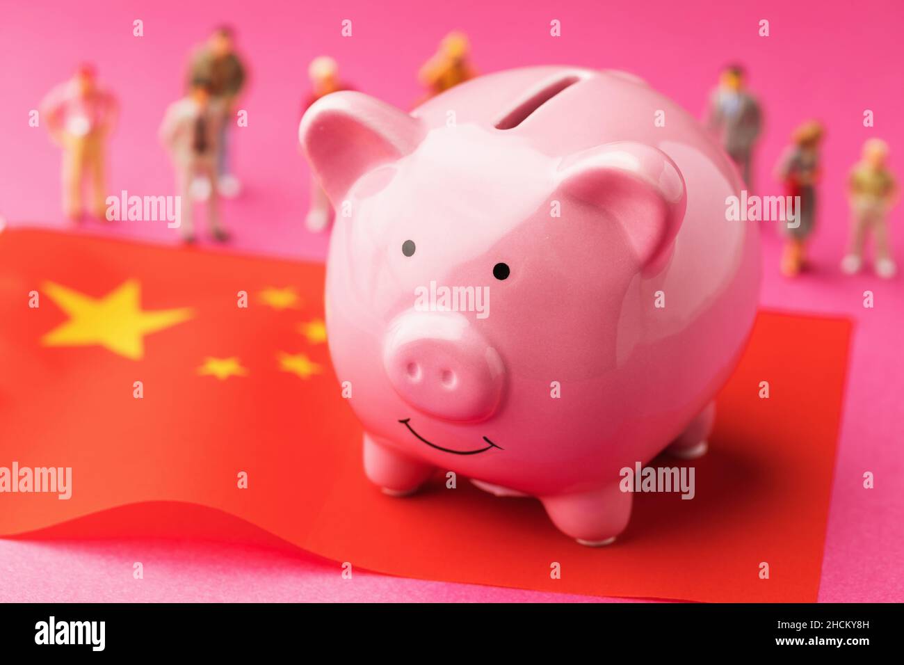 Piggy bank, Chinese flag and plastic toy men on a colored background