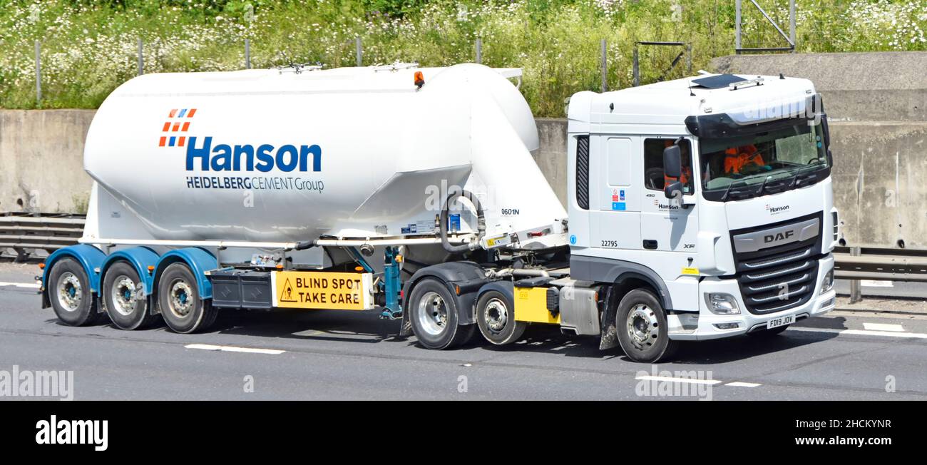 Brand & logo advertising side & front view of Hanson Heidelberg cement lorry truck Blind Spot warning on bulk tanker trailer driving along UK motorway Stock Photo