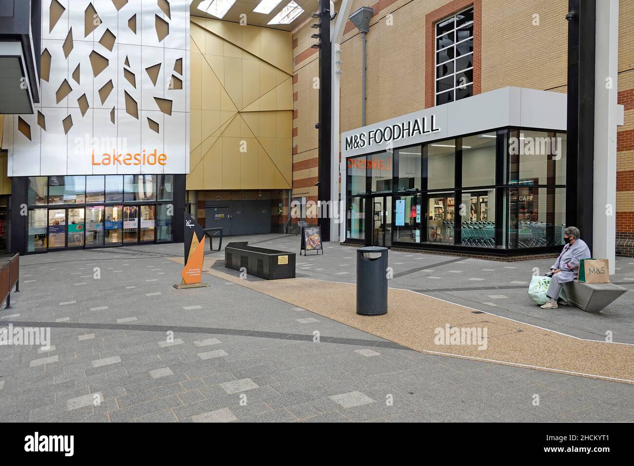 Lakeside shopping center entrance doors & sign with M&S Food Hall access to Marks and Spencer retail store alone shopper wearing Covid face mask UK Stock Photo
