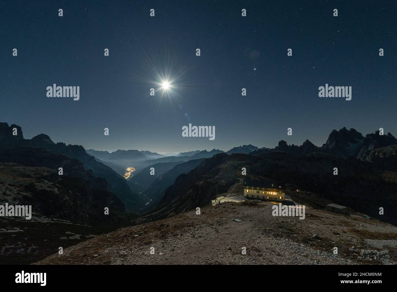 View from the Auronzo Hut below the Tre Cime di Lavaredo south towards mountain ranges and peaks of the Dolomites in the bright moonlight, Italy Stock Photo