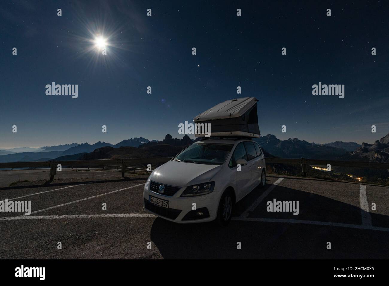 Van with roof-top tent at the Tre Cime di Lavaredo with view of mountain ranges and peaks of the Dolomites in the bright moonlight, Italy Stock Photo